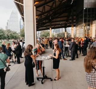 People with event badges on standing under the pavilion at Palmer Events Center during golden hour.
