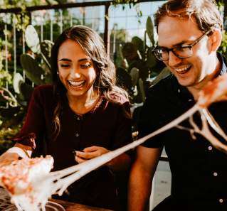 Couple pulling two pieces of cheesy pepperoni pizza apart from Via 313