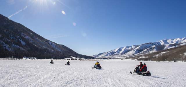 Group of snowmobiles in a wide-open field in Weber Canyon on sunny day.