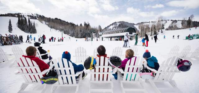 A family relaxes on white adirondack chairs at the Silver Lake ski beach in Park City, UT