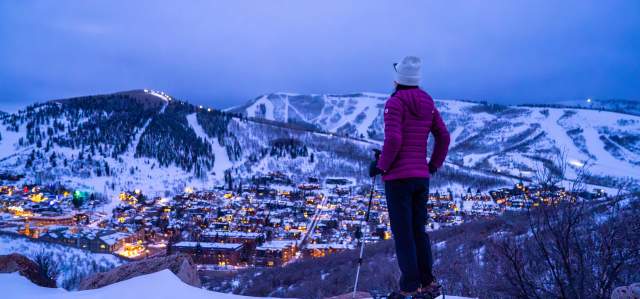 A snowshoer gazes over Park City at dusk in the winter