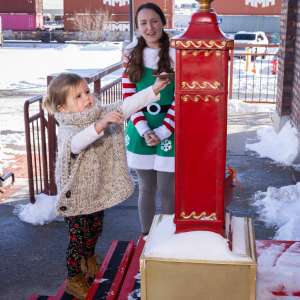 a child puts a letter to santa in the red mailbox