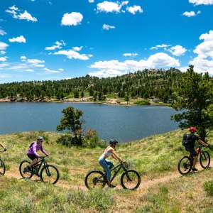 Four people riding mountain bikes around a lake