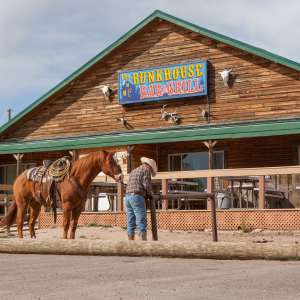 A man ties a horse up in front of a bar