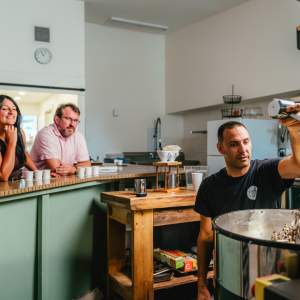 Elio roasting coffee as experience attendees view from the counter and sip on coffee