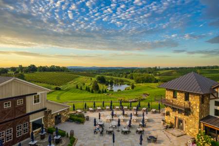 Aerial view of Stone Tower Winery's outdoor patio and rolling vineyard at sunset in Leesburg, Virginia.