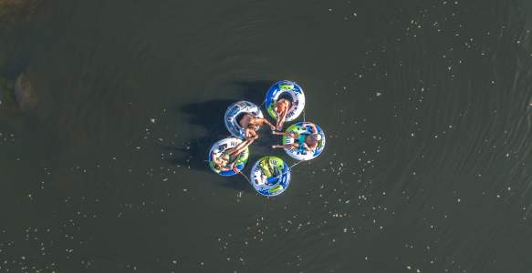 The overview of five tubes with adults sitting in them on a lake