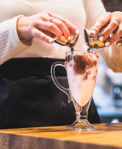 woman pouring chocolate into a glass of milk
