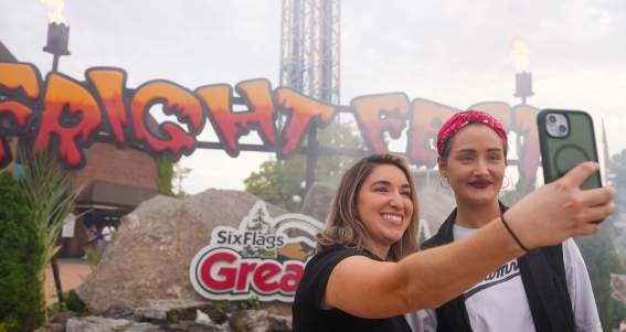 Two women taking a selfie in front of the Fright Fest sign at Six Flags Great Escape