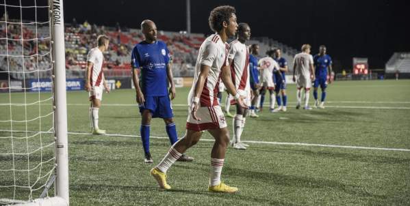 Loudoun United FC and opposing players line up near the goal during a night match at Segra Field in Loudoun County, Virginia