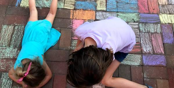 Two girls playing with sidewalk chalk