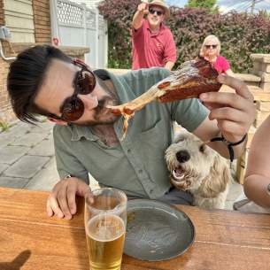 Man taking a bite out of a cheesy slice of pizza at Aurora Brewing company