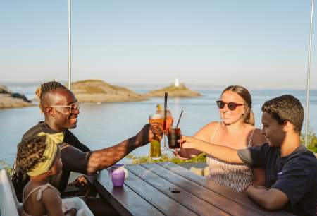 Family toasting their glasses with coast in the background