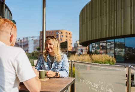Young couple drinking coffee with Swansea arena in the background
