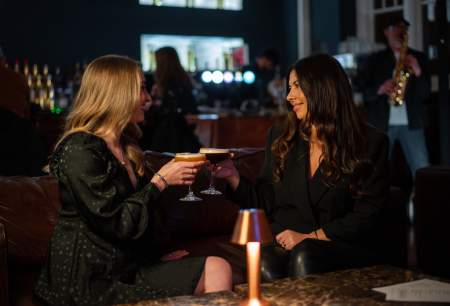 Two women sharing cocktails in a bar