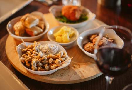 Battered cockles in a bowl with a glass of red wine.