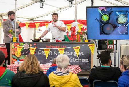 chef doing a live cooking demonstration to a crowd of people