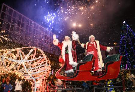 Father Christmas and Mrs Claus waving from their sleigh while fireworks go off in the swansea christmas parade