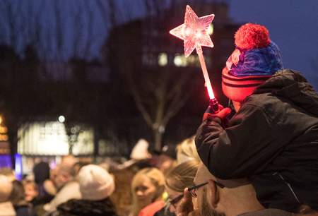 A young boy holding a star wand at the Christmas Parade