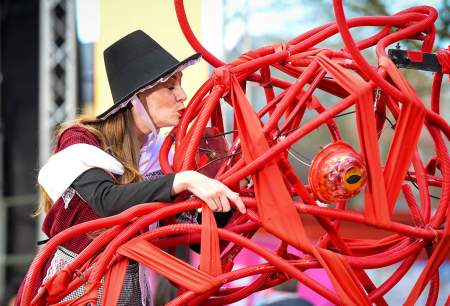 A woman in traditional Welsh dress kissing a large mechanical dragon.