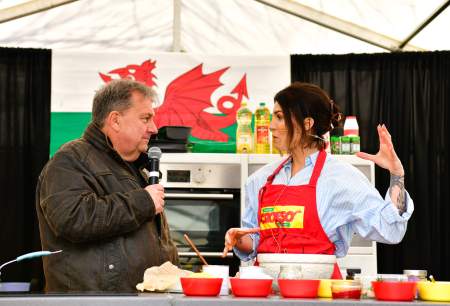 A man interviewing a woman chef in front of a Welsh flag