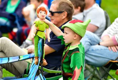A small boy dresses as Peter Pan holding a Peter Pan doll