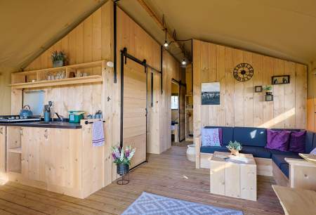 A wooden cabin with a kitchen and seating area.