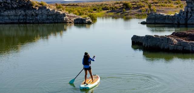 A woman stand up paddleboarding at Elephant Butte State Park near Truth or Consequences, New Mexico