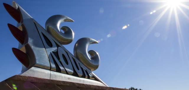 a large silver statue mimicking the taillights of an older style vehicle glistens in the bright sun, the statue reads "Route 66"