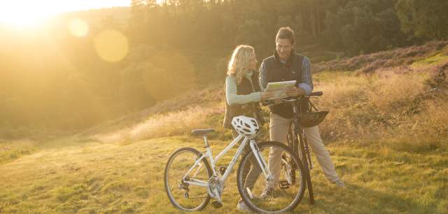 Cannock Chase heathland Autumn sunshine couple on bikes stopping to read map