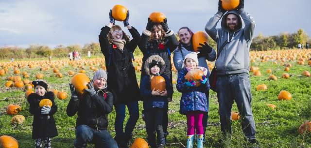 family with their pumpkin haul in the patch