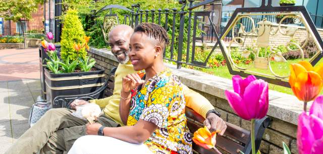 couple sit on bench by floral display diversity
