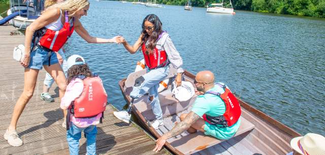 rowing boat visitor with prosthetic leg is helped out of boat