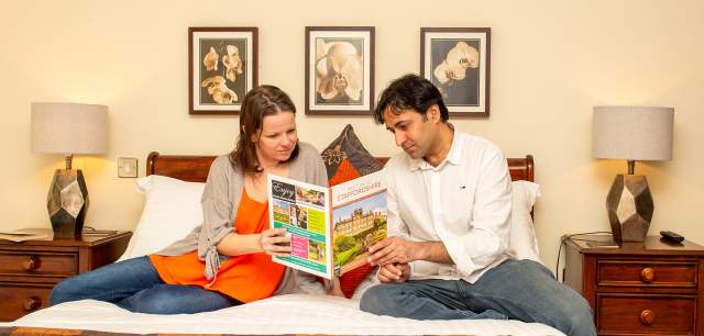 couple sit on bed reading guide book