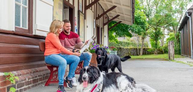 couple sit on bench by Manifold Visitor Centre reading leaflet