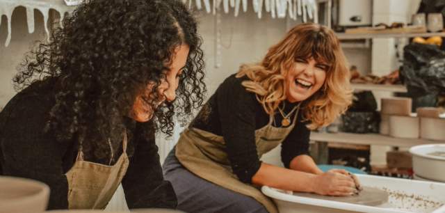 two friends laughing in a pottery class
