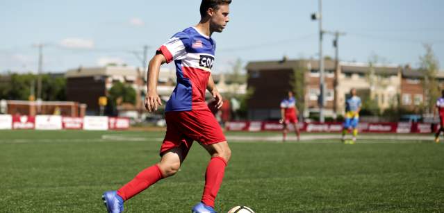 A soccer player dribbling a ball across a field.