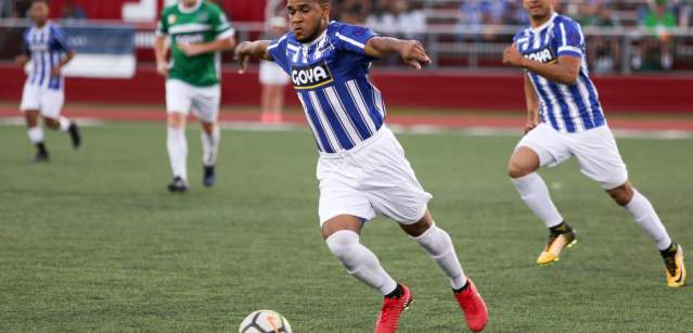 Male soccer players fighting for a ball, with one player prepared to kick the ball.
