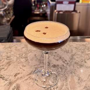 Espresso martini with coffee bean garnish on a marble bar counter at Cap City Fine Diner in Dublin, Ohio.