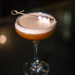 Getaway's "Campfire Song" Espresso martini garnished with three mini marshmallows on a cocktail pick, served in a coupe glass on a dark bar surface.