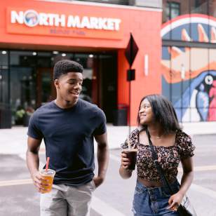 A young boy and girl walking out of the North Market Bridge Park with bubble teas in hand.