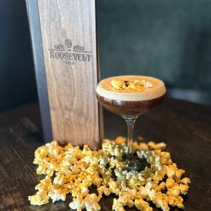 Espresso martini garnished with popcorn and coffee beans, surrounded by popcorn at The Roosevelt Room.