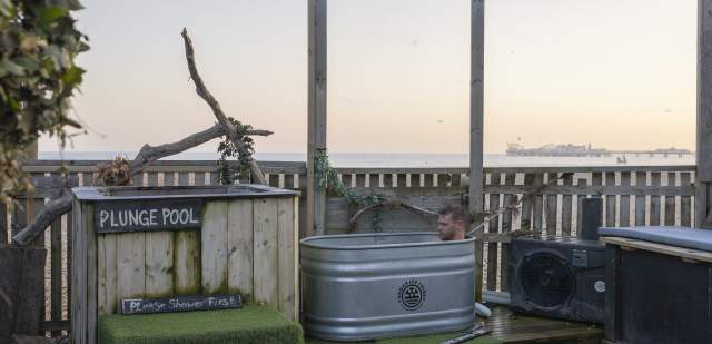 A man sits in a tin ice bath, next to a plunge pool at the Beach Box Sauna, Sussex