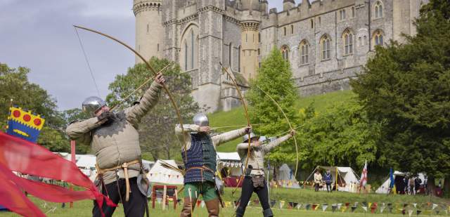 Three archers taking aim in medieval costume in the grounds of Arundel Castle in Sussex
