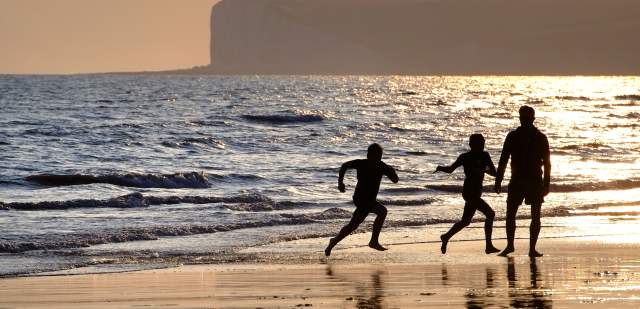 A family playing on the beach at sunset at Birling Gap, Sussex