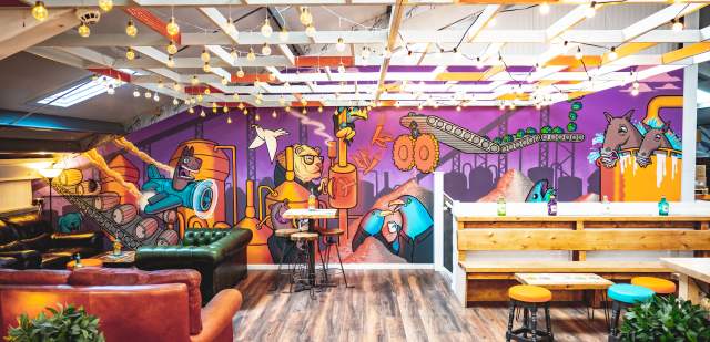 Colourful purple and blue wall mural and sofa seating area at Firebird brewery