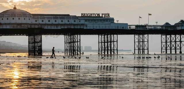Brighton pier at low tide with the sun rising in the background