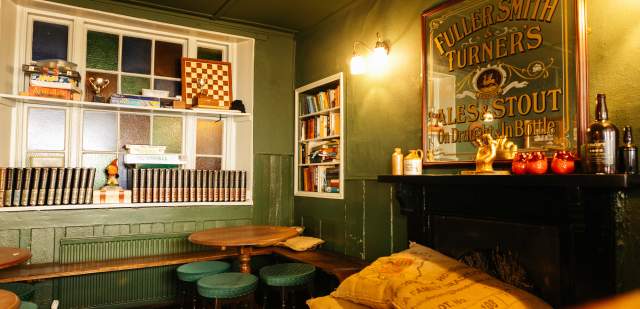Interior of Lewes Arms pub, with green walls, chairs and pub memorabilia
