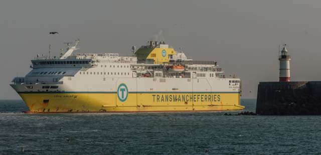 Yellow and white cross channel ferry coming in to port at Newhaven, with lighthouse in view