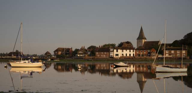 Boats moored on the quay at Bosham Harbour with church in the background